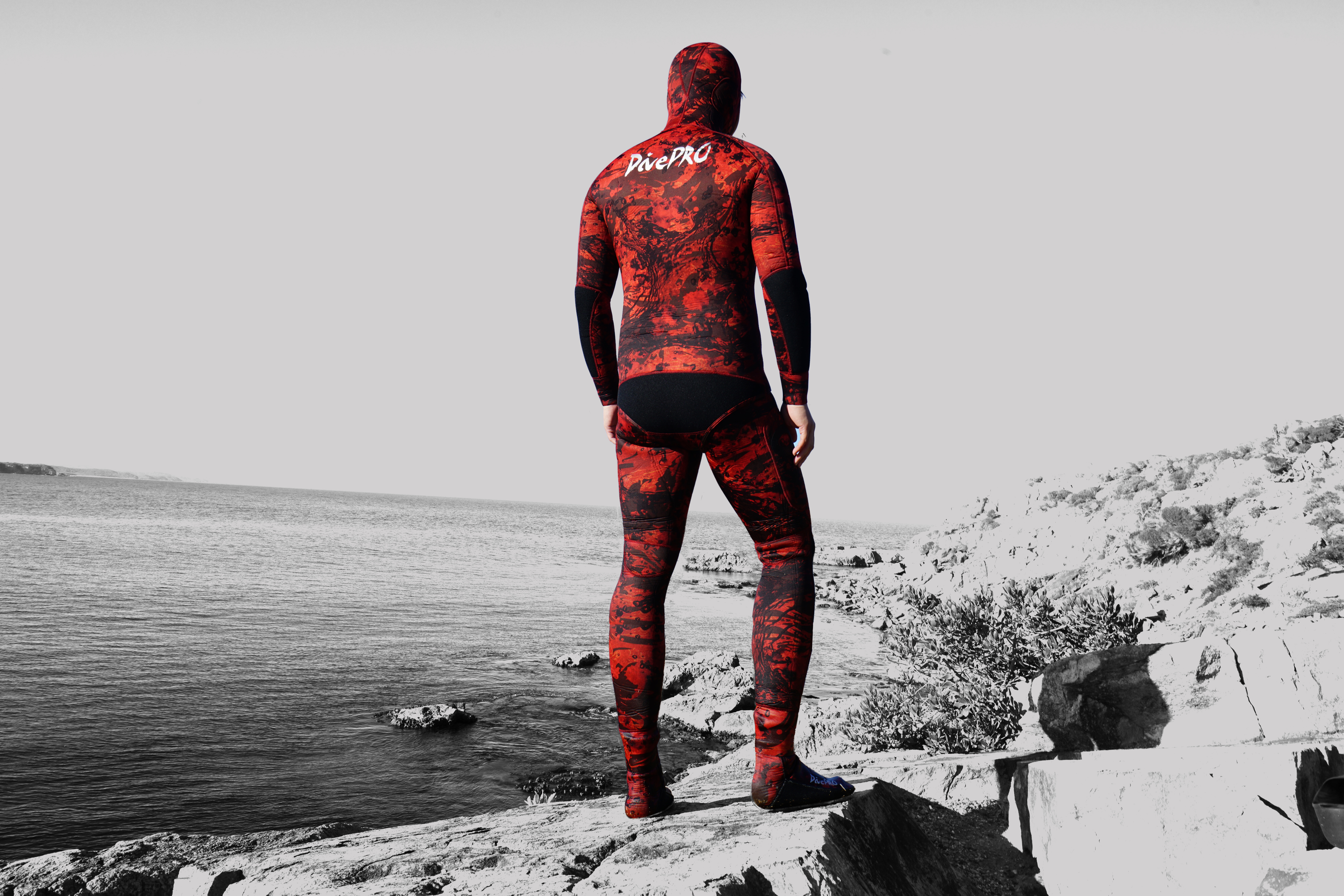DivePRO diver in a red wetsuit looking over the coast